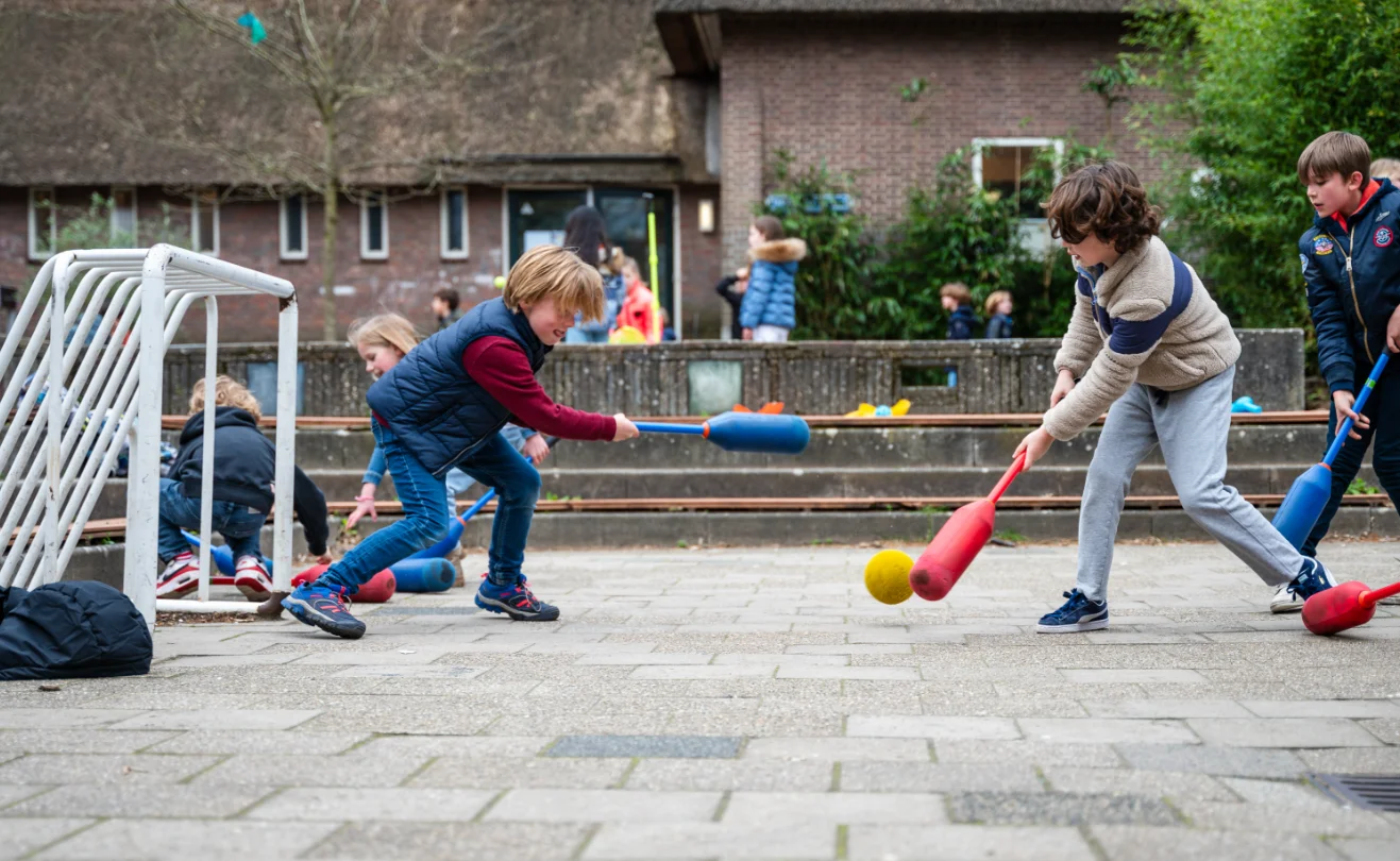 Kinderen spelen met sportmateriaal tijdens pauzesport op het schoolplein